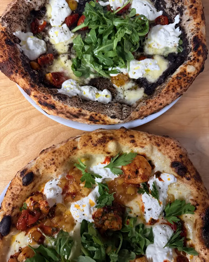 Two pizzas on a wooden table