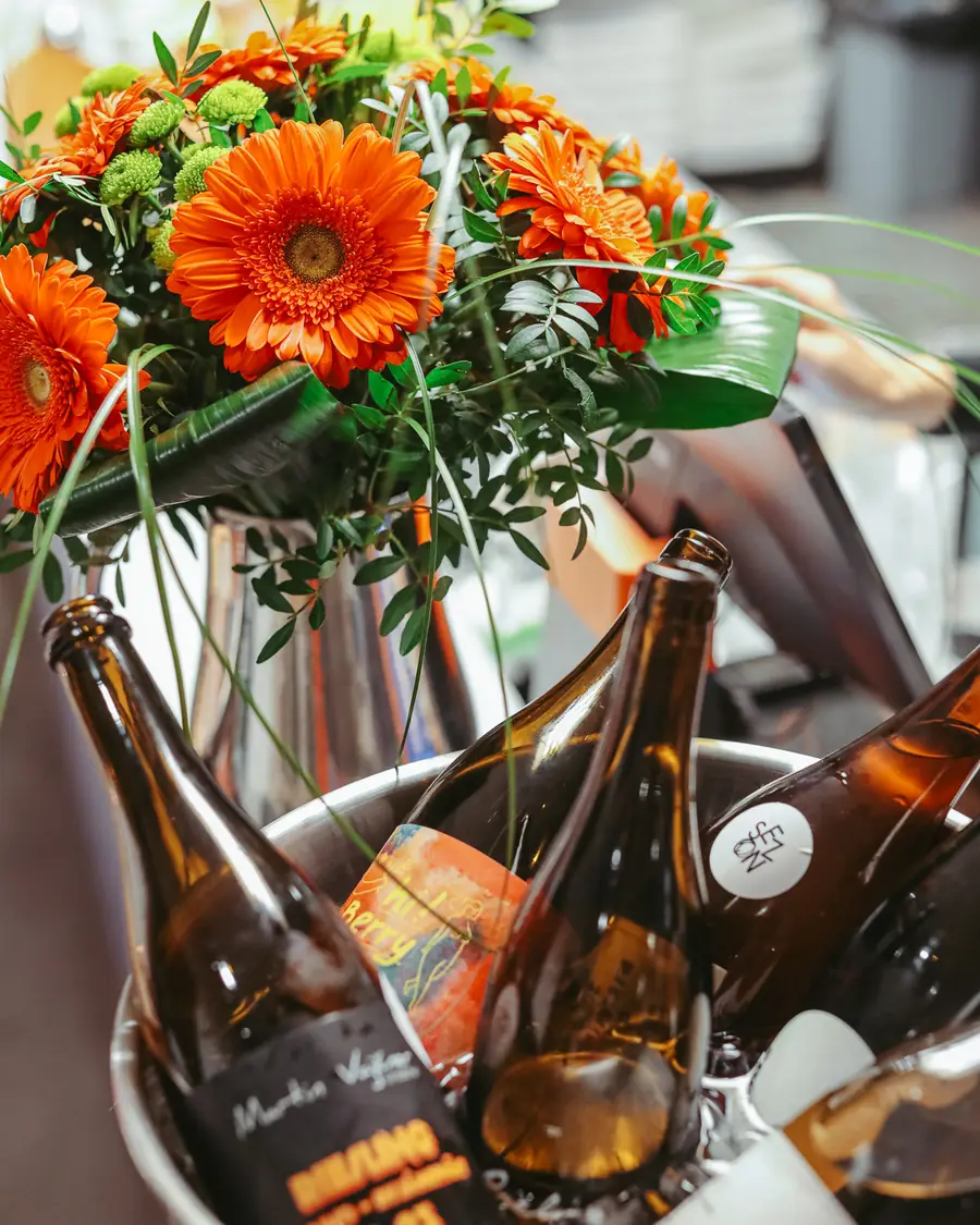 Natural wine bottles in an ice bucket with orange gerberas