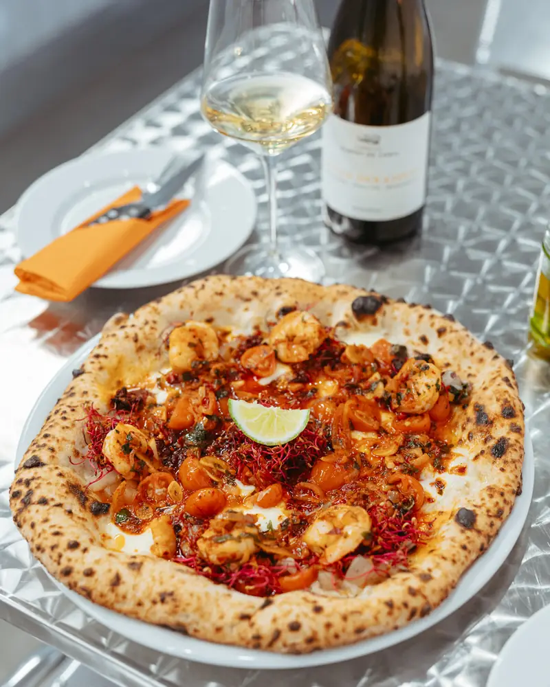 Pizza and a bottle of white wine on a table